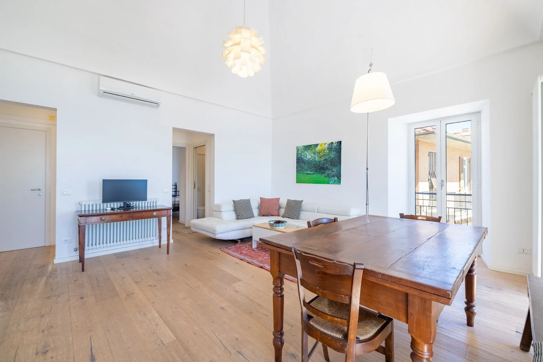 A bright living and dining area with a wooden table and seating.