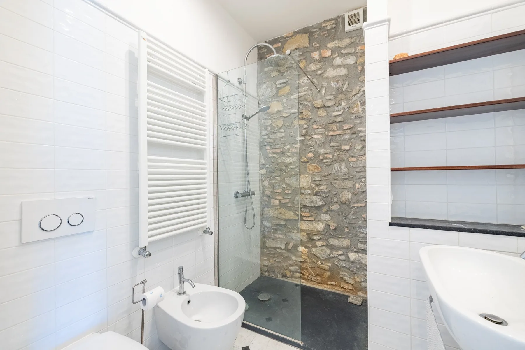 A bright bathroom with a glass shower and wall-mounted sink.