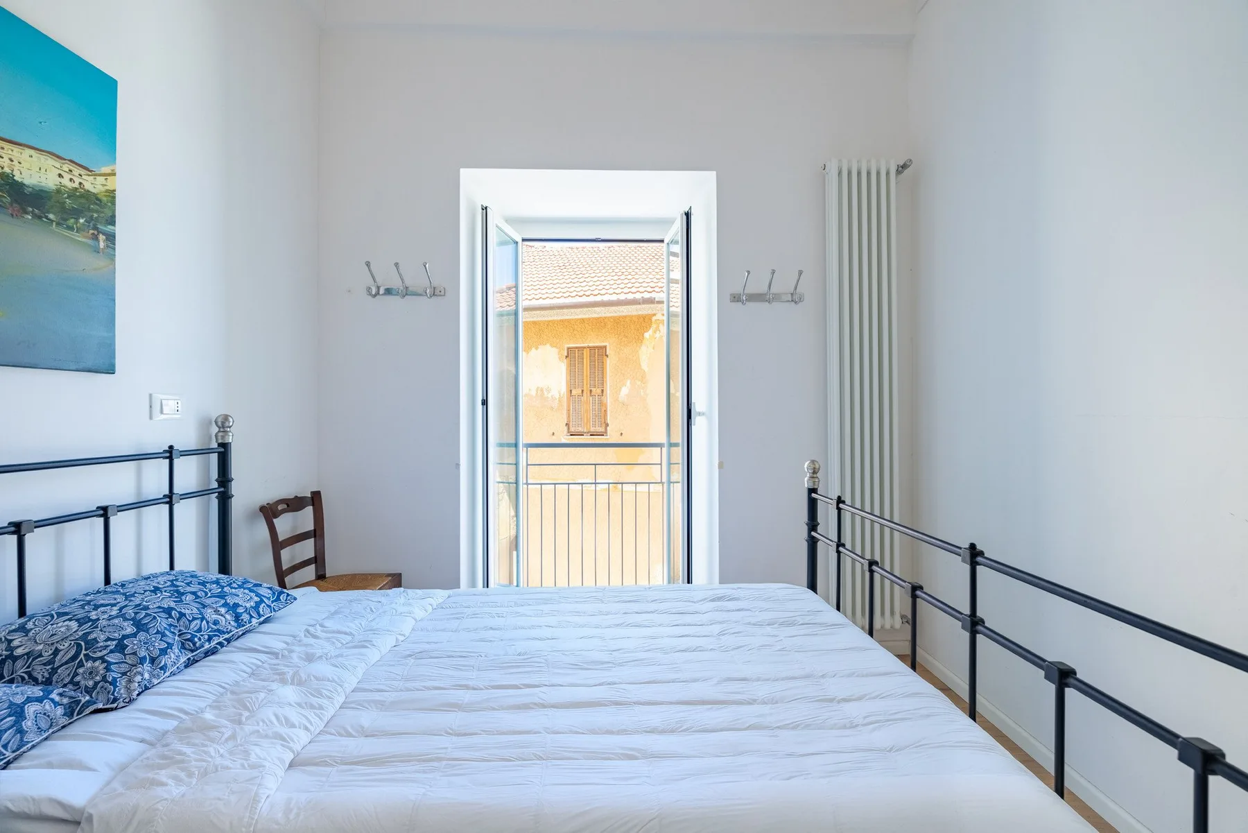 A bright bedroom with a bed facing an open balcony door.