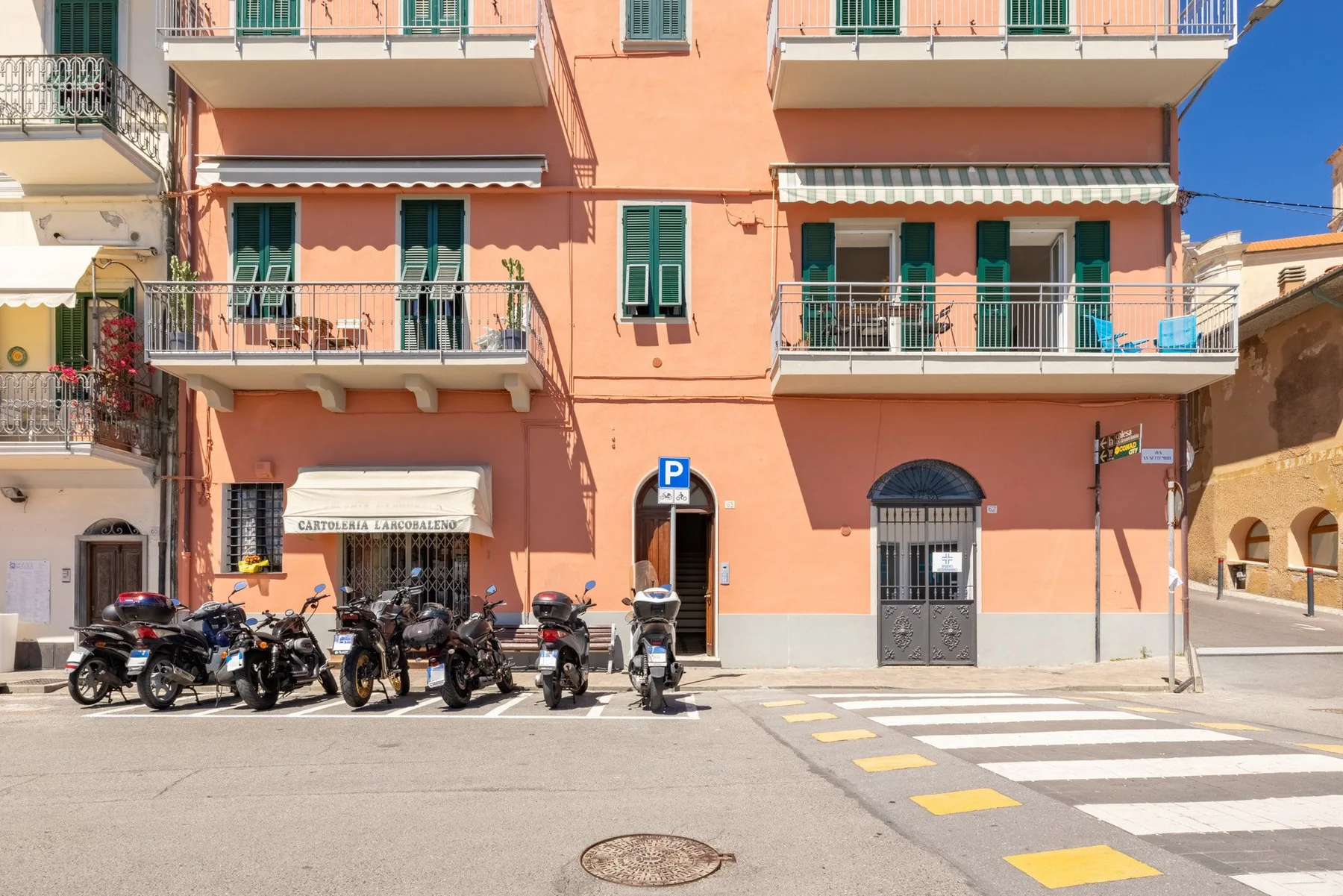 A peach-colored apartment building with balconies and parked scooters along the street.