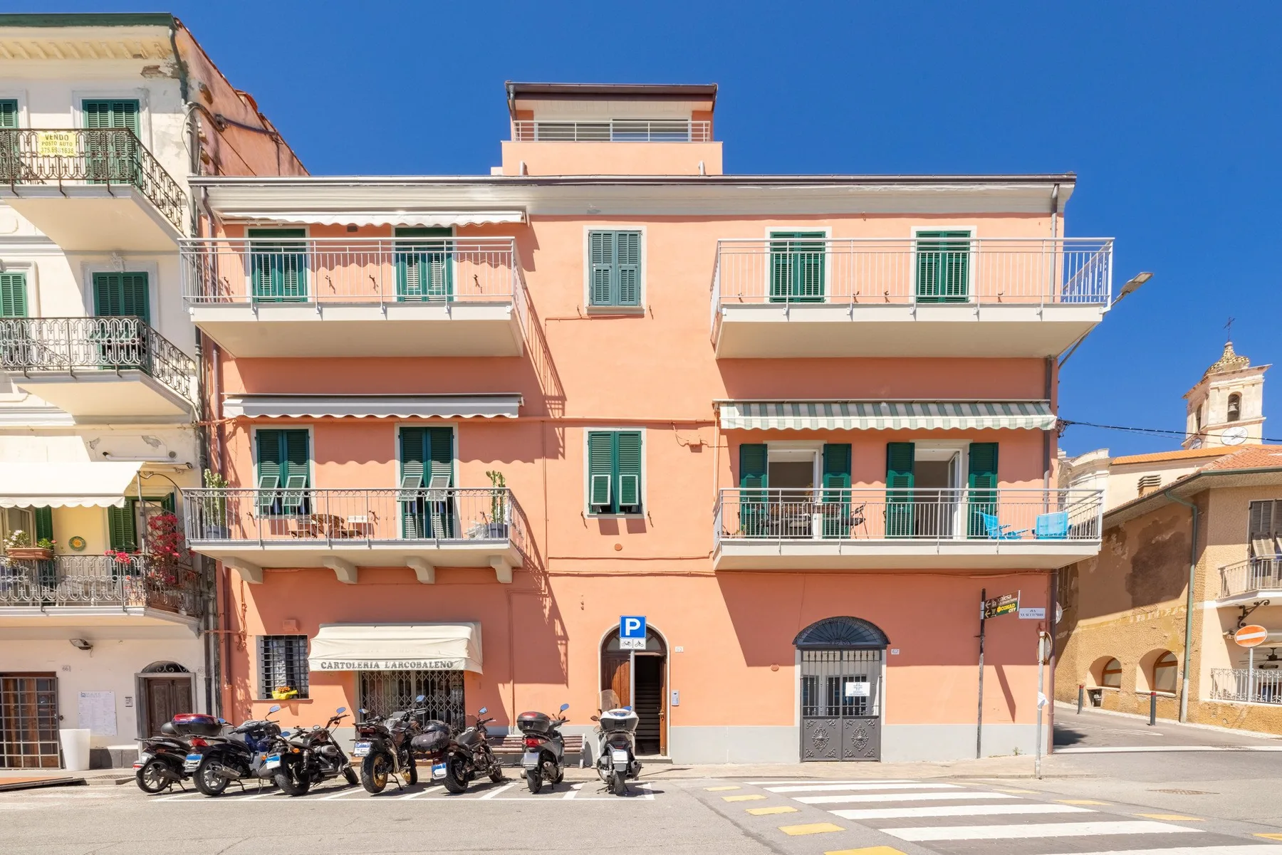 A peach-colored multi-story building with balconies faces a paved street.