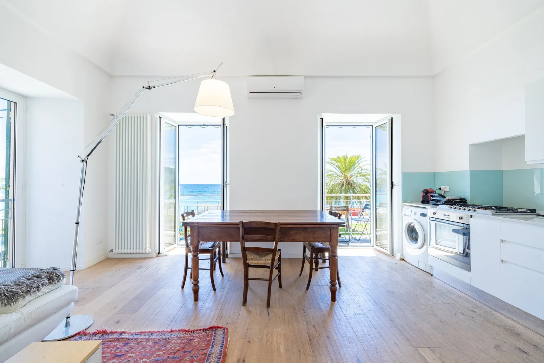 A bright dining area with a wooden table beside large windows.