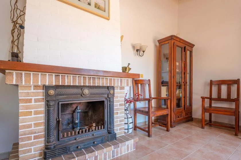 A living room with a brick fireplace and wooden seating.