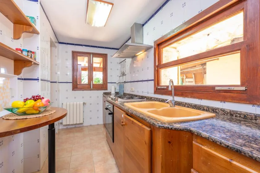 A tiled kitchen with wooden cabinets, a sink, and a window.