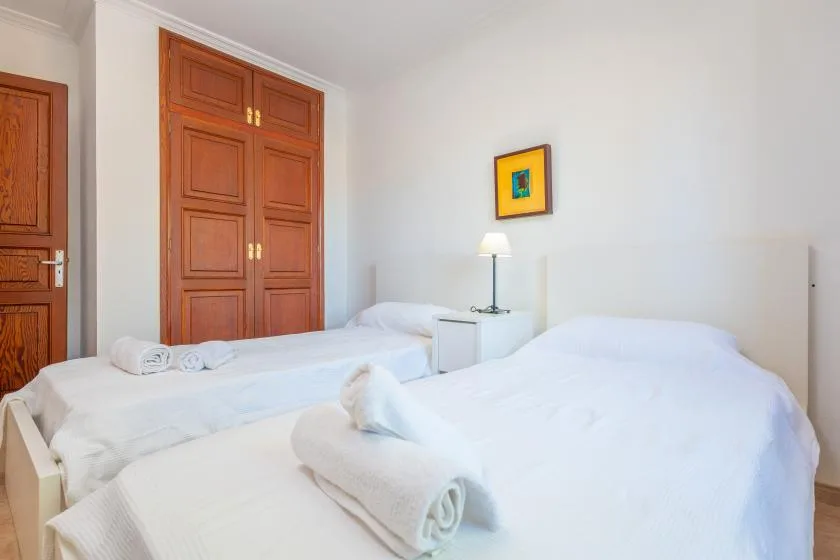 A bedroom with white beds, wooden doors, and a bedside lamp.