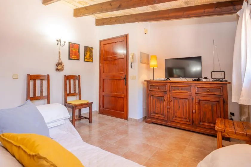 A bedroom with a bed, wooden chairs, and a television on a cabinet.