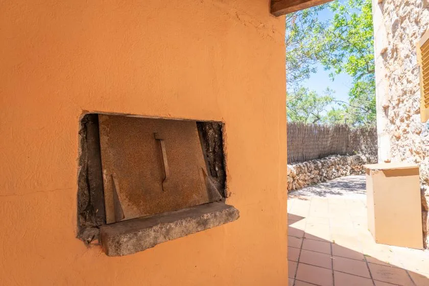 An outdoor patio beside an orange stucco wall with a recessed opening.
