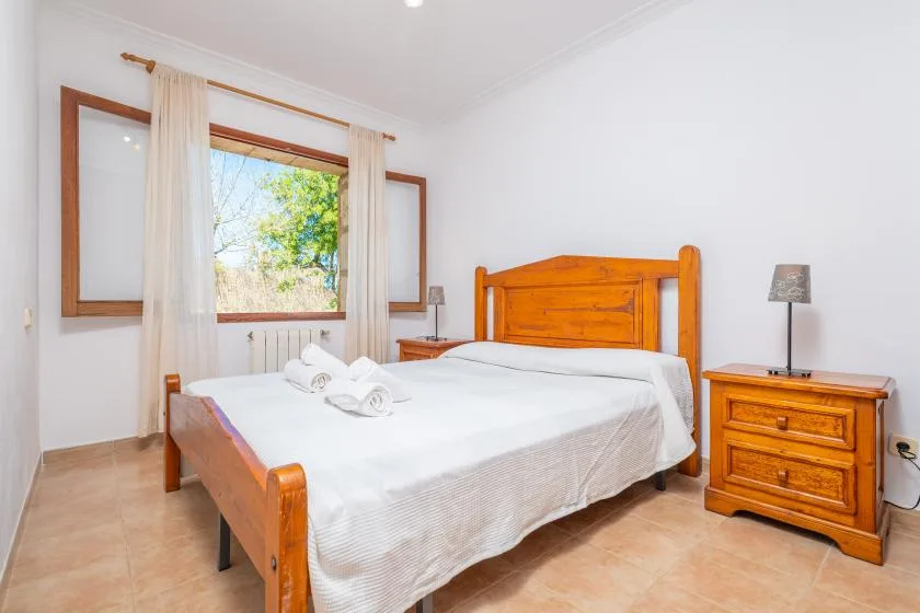 A bedroom with a wooden bed, white bedding, and a bedside table.