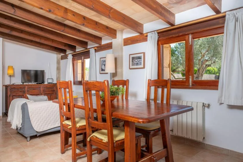 A dining area with a wooden table and chairs beside a bed.