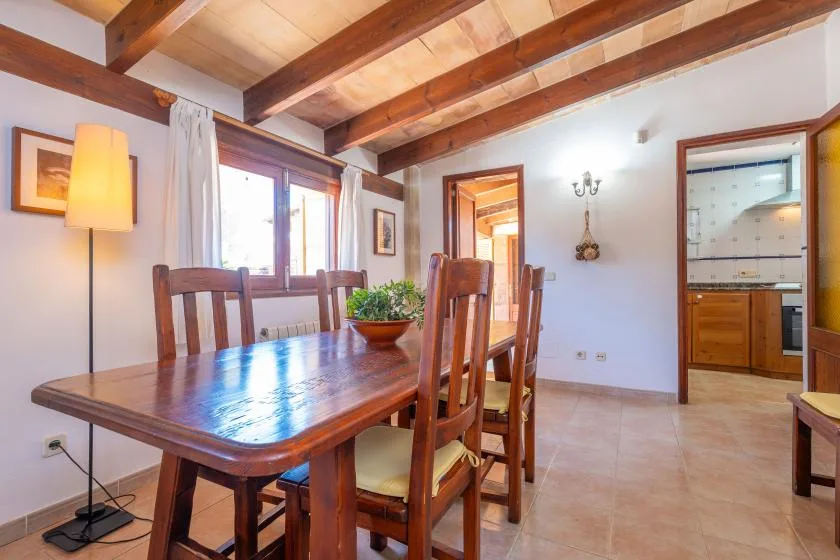 A dining area with a wooden table and chairs beneath exposed ceiling beams.