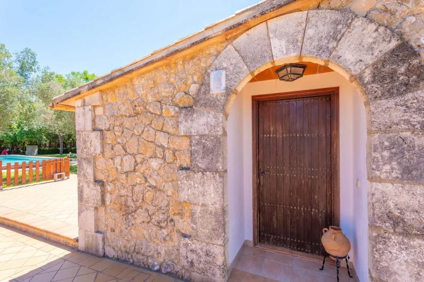 A stone building entrance with an arched doorway and dark wooden door.