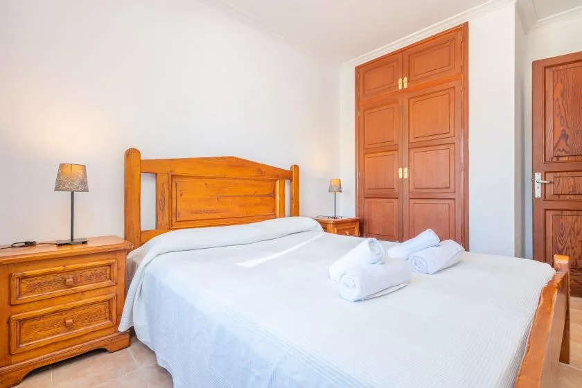 A bedroom with a wooden bed, white bedding, and matching wooden furniture.