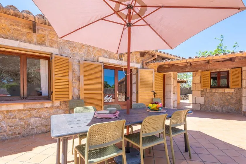 An outdoor dining area with a table and seating beneath a large umbrella.
