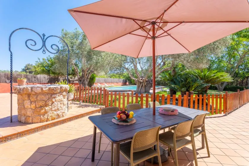 A tiled patio dining area with a table beneath a large pink umbrella.