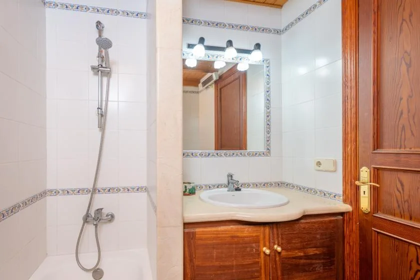 A tiled bathroom with a shower, sink, and mirror.