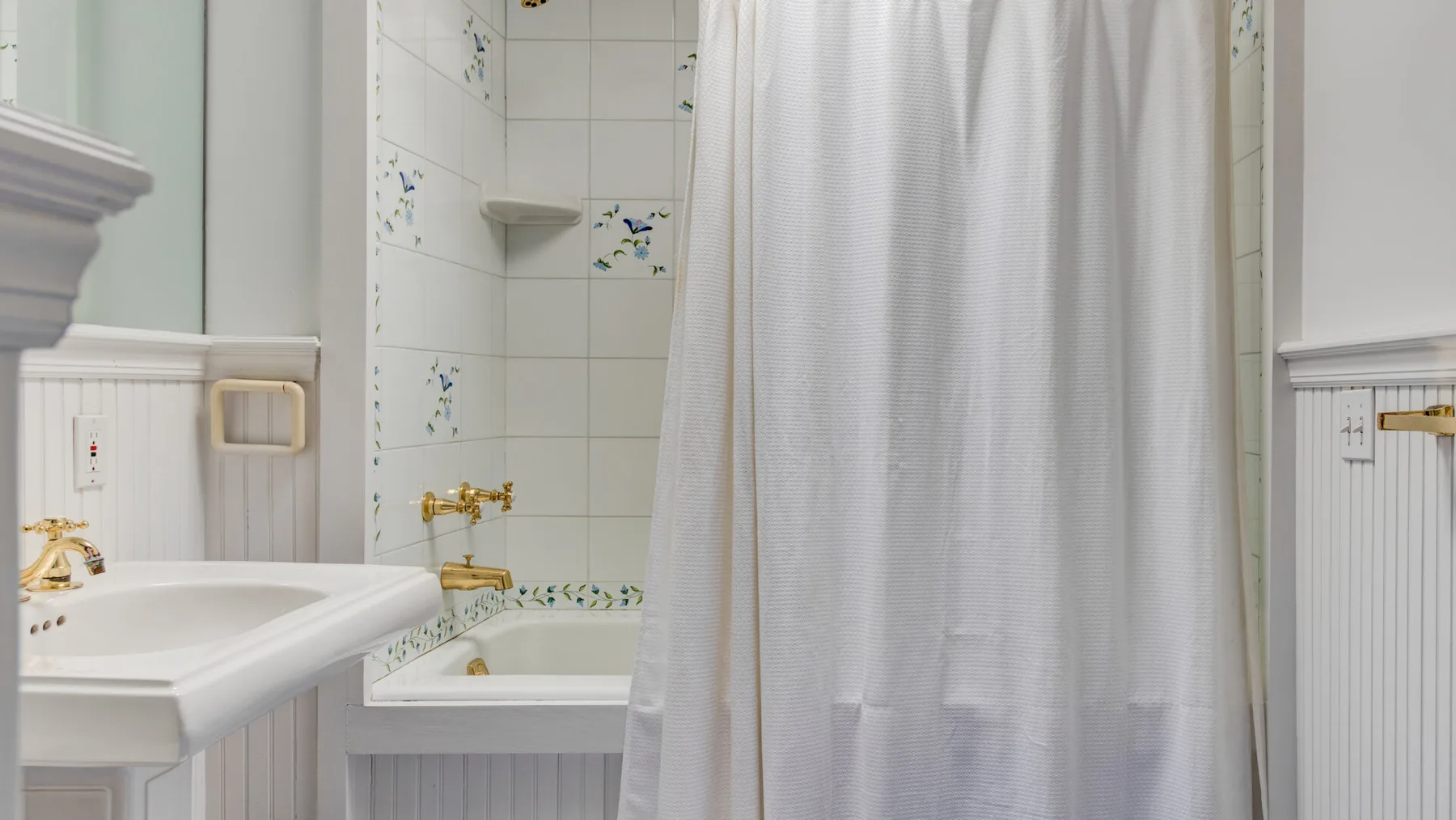 A tiled bathroom with a sink beside a bathtub and shower curtain.