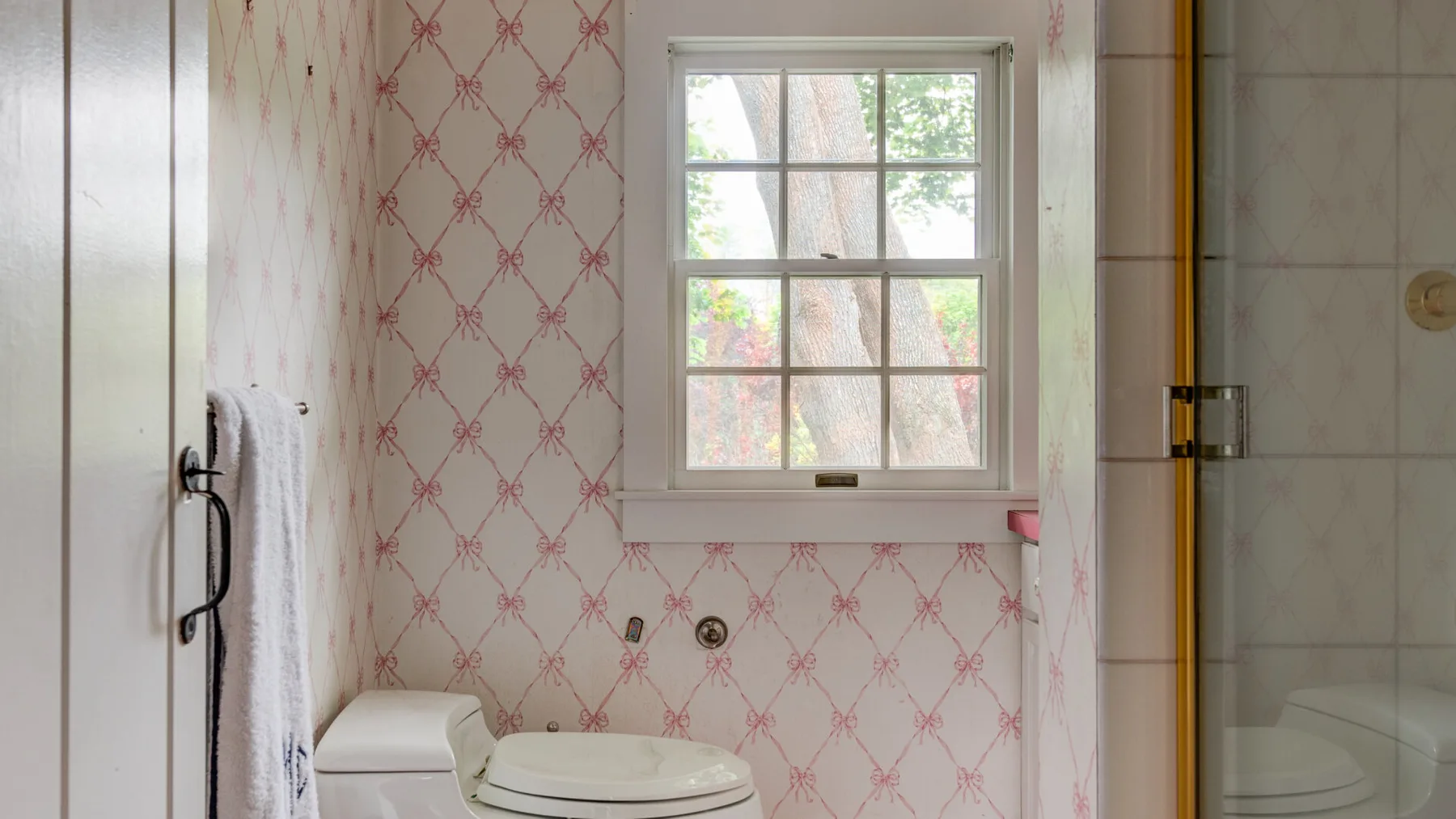 A bathroom with a window, toilet, and shower.