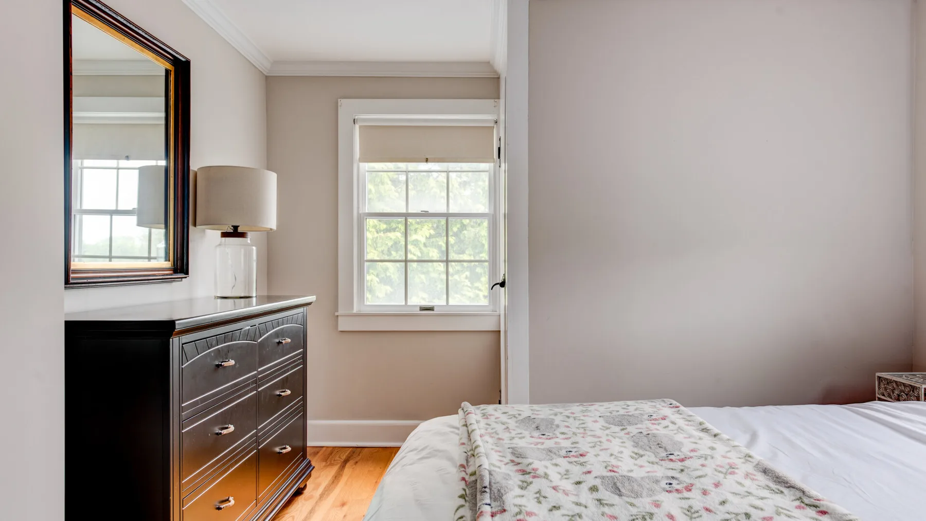A bedroom with a bed, dresser, and window.
