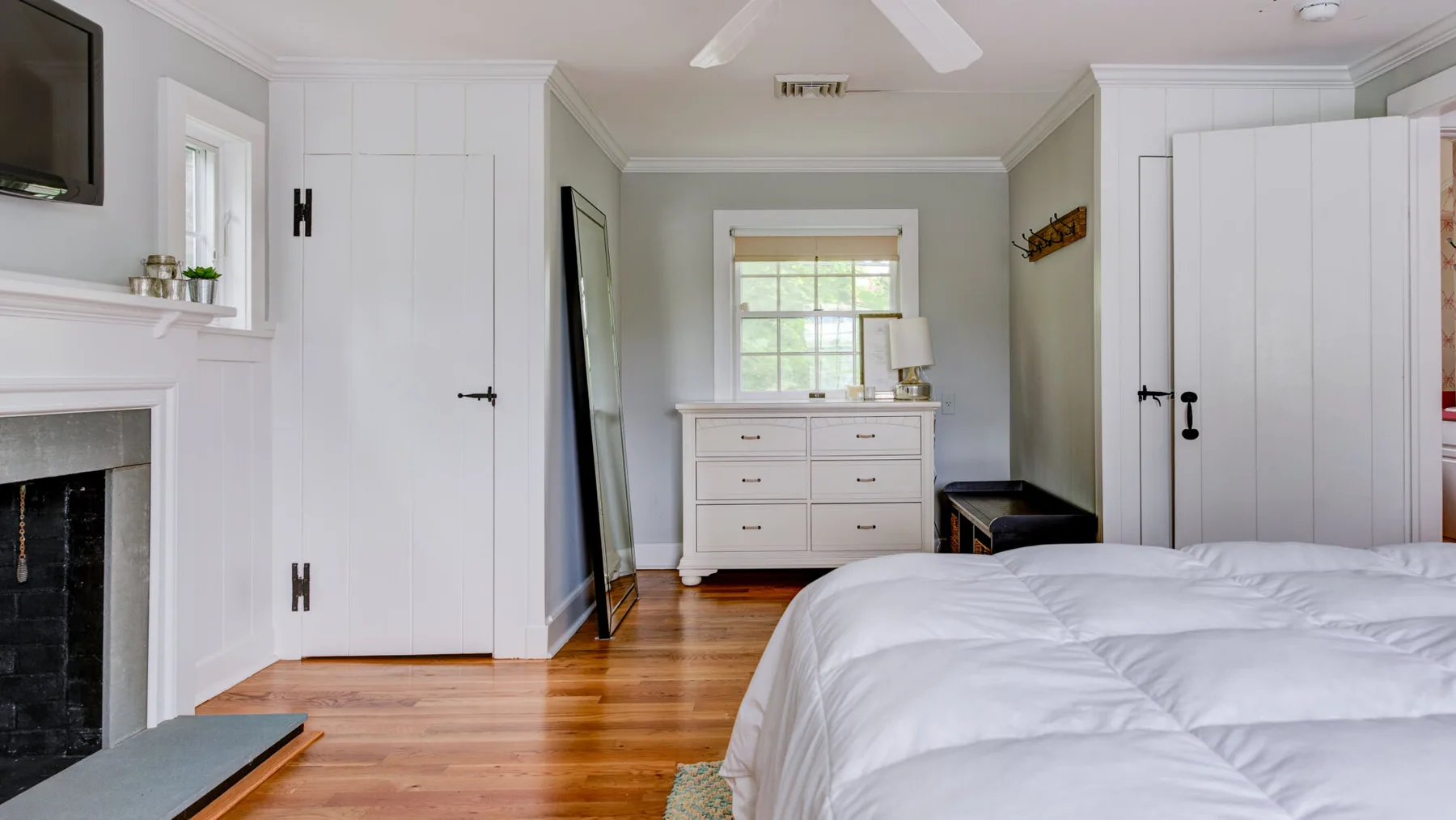 A bedroom with a bed, white storage cabinets, and a window.