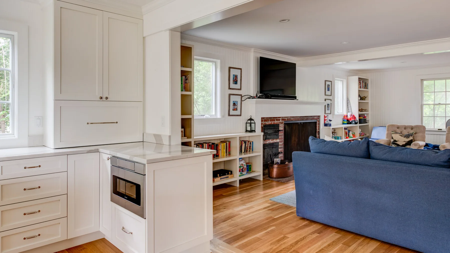 A bright open-plan living room and kitchen with a blue seating area and fireplace.