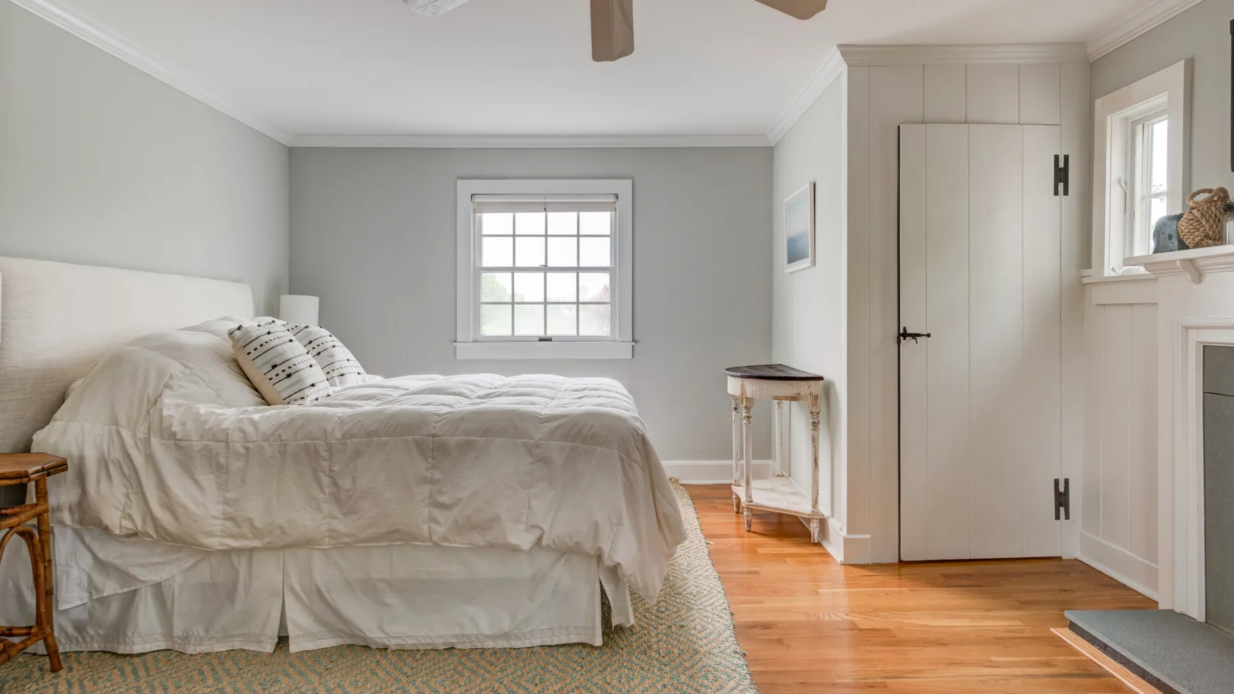 A bedroom with a bed, a window, and light wood flooring.