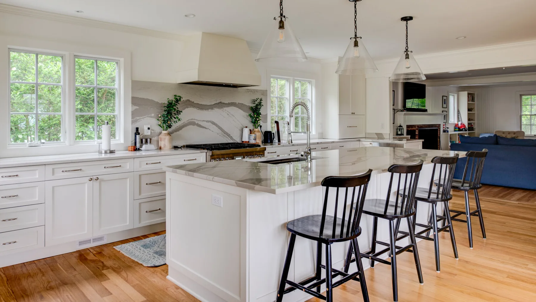 A bright kitchen with a large island and seating beside the living area.