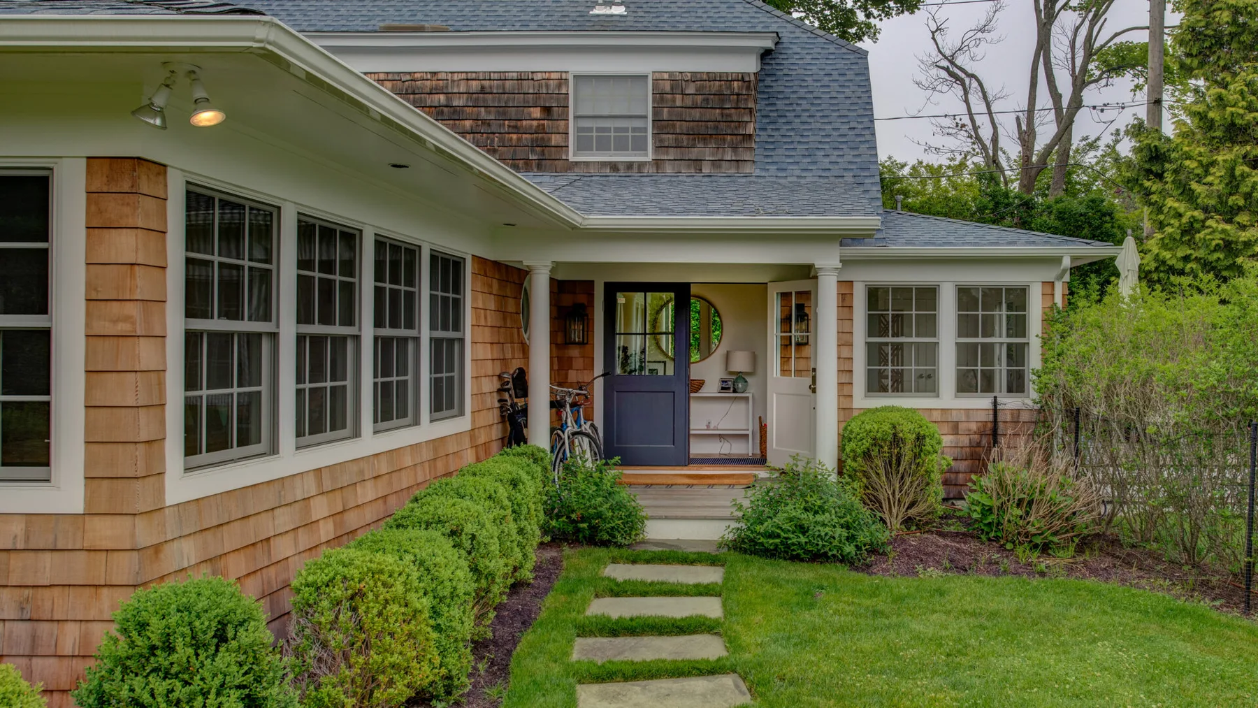 A house entrance opens onto a front garden with a stepping-stone path.