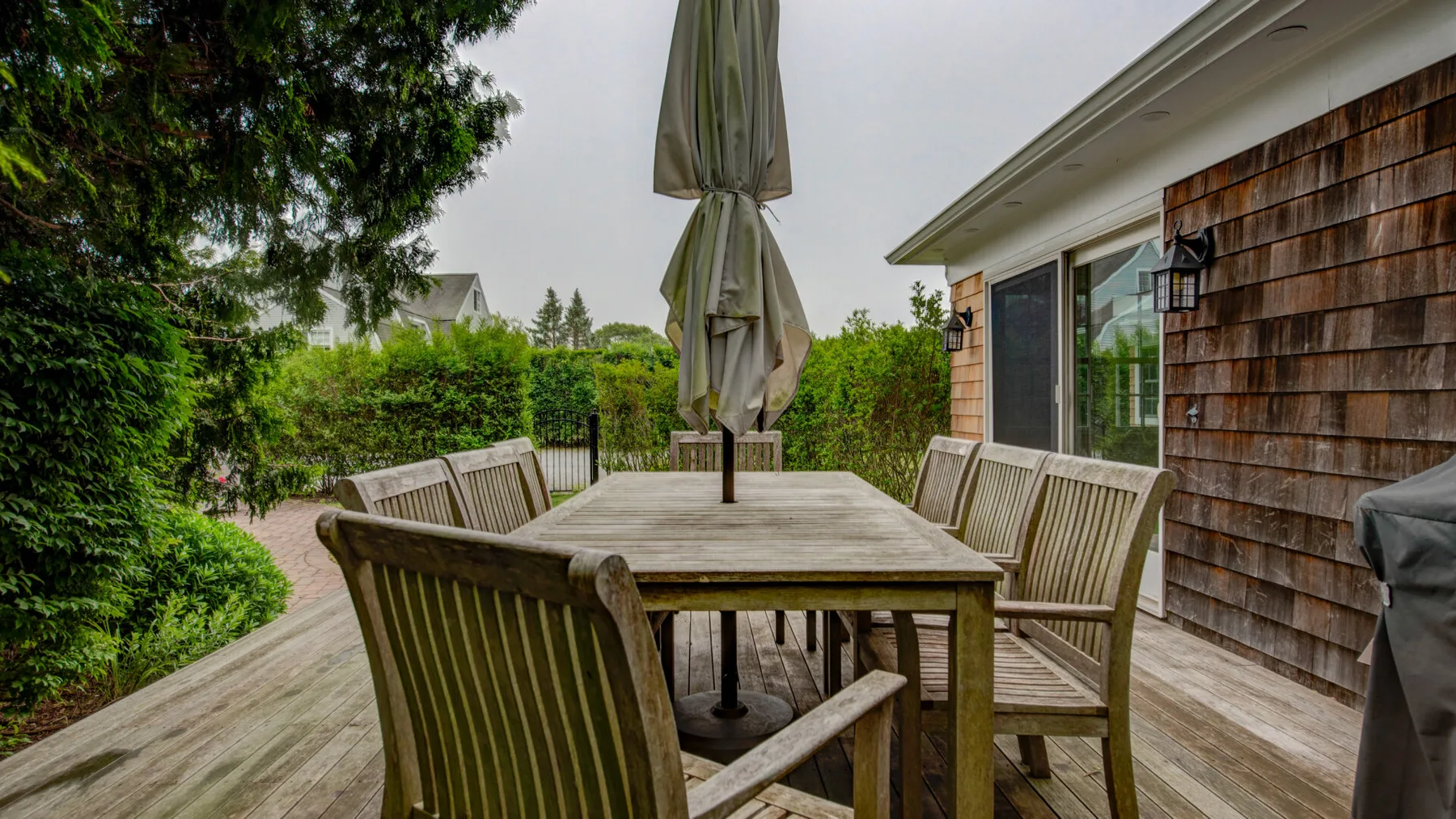 An outdoor dining area with wooden seating and a closed patio umbrella.