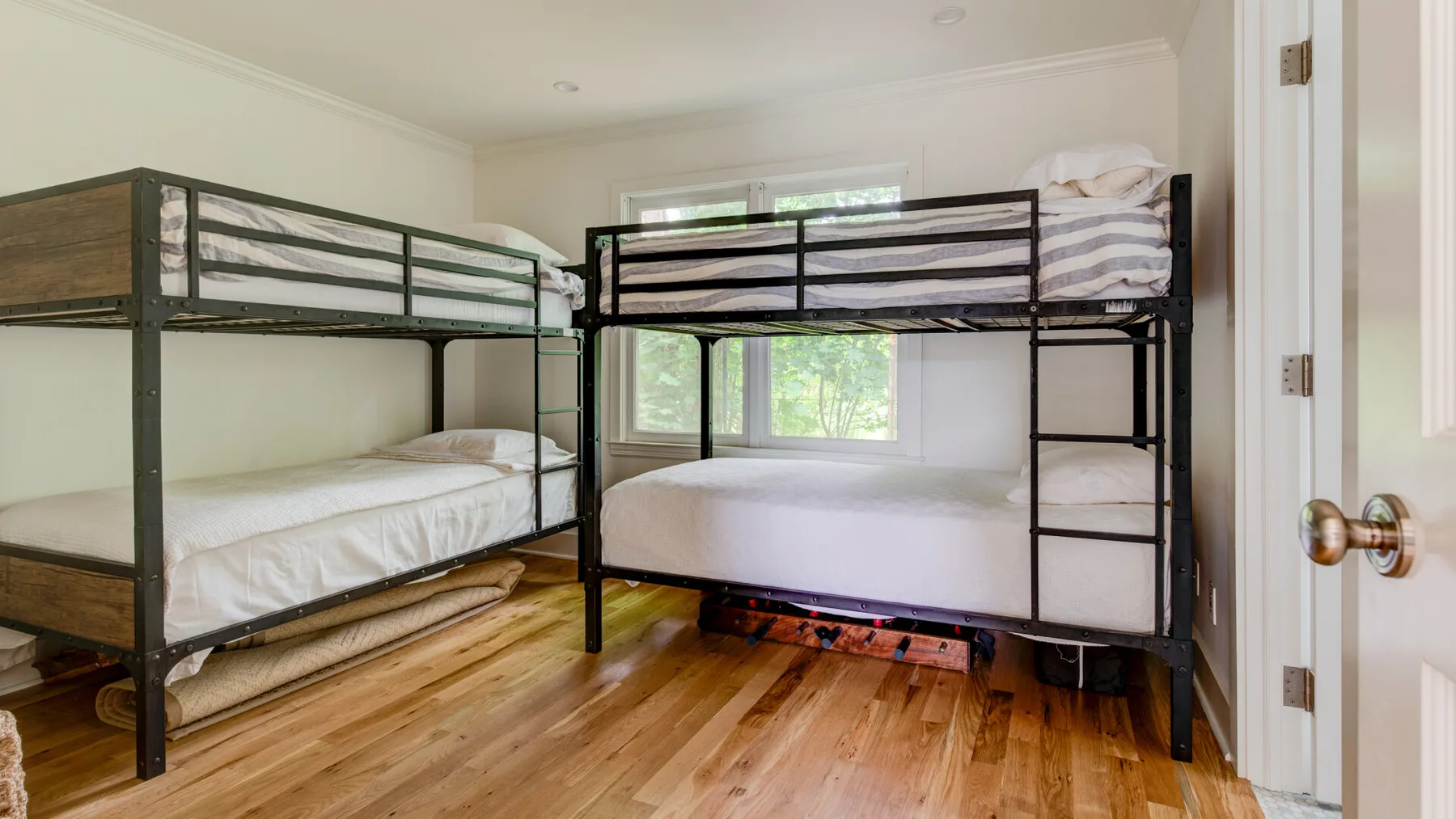A bedroom with two black metal bunk beds and wood flooring.