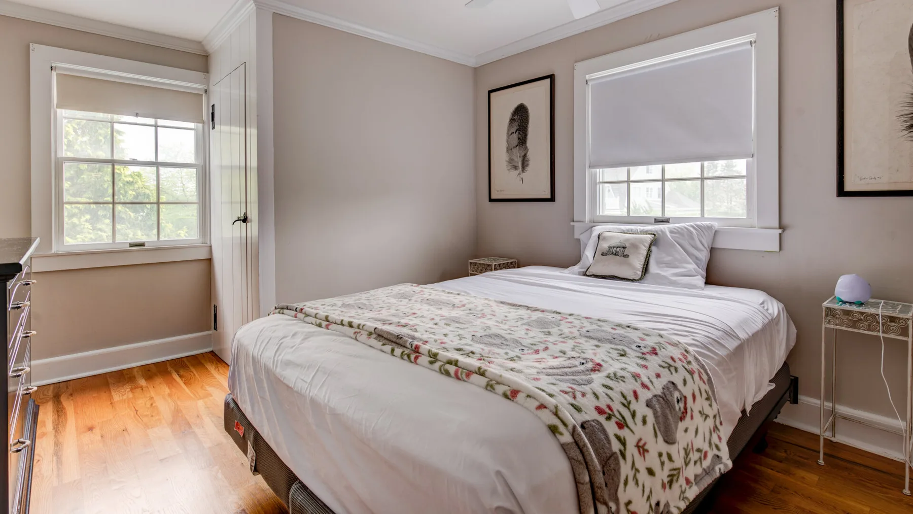 A bedroom with a bed, patterned bedding, and windows.