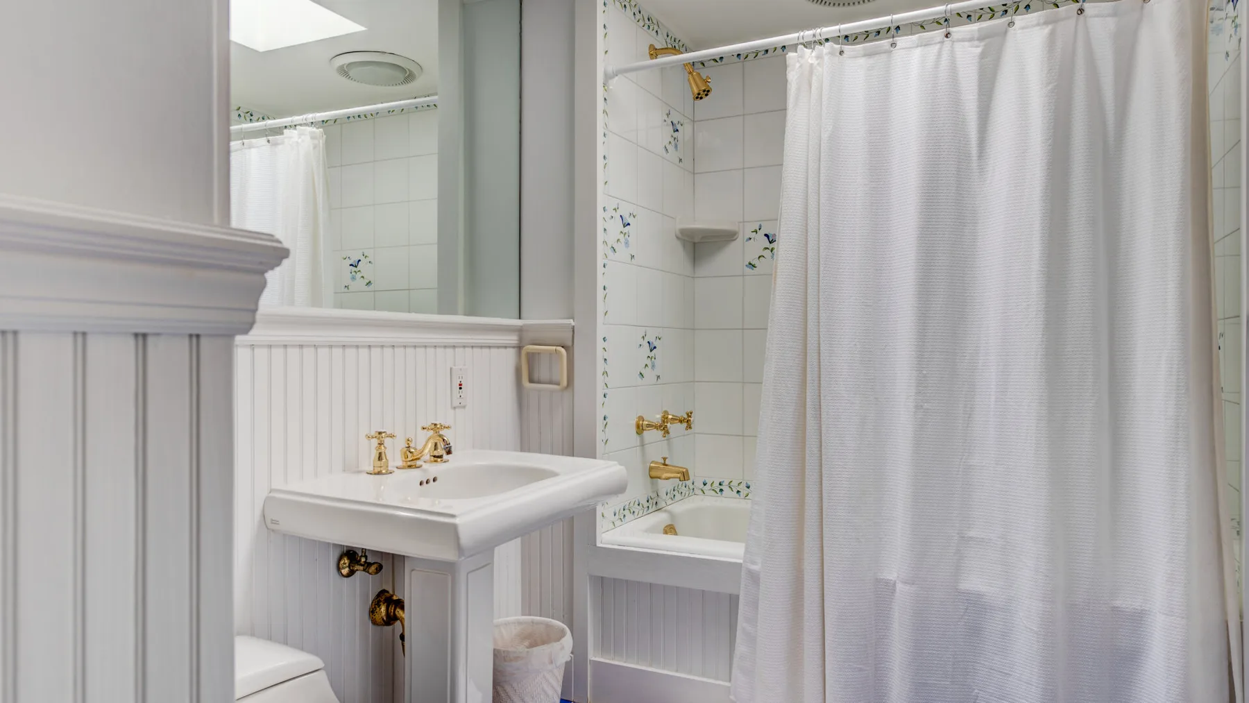 A tiled bathroom with a sink and a shower curtain.