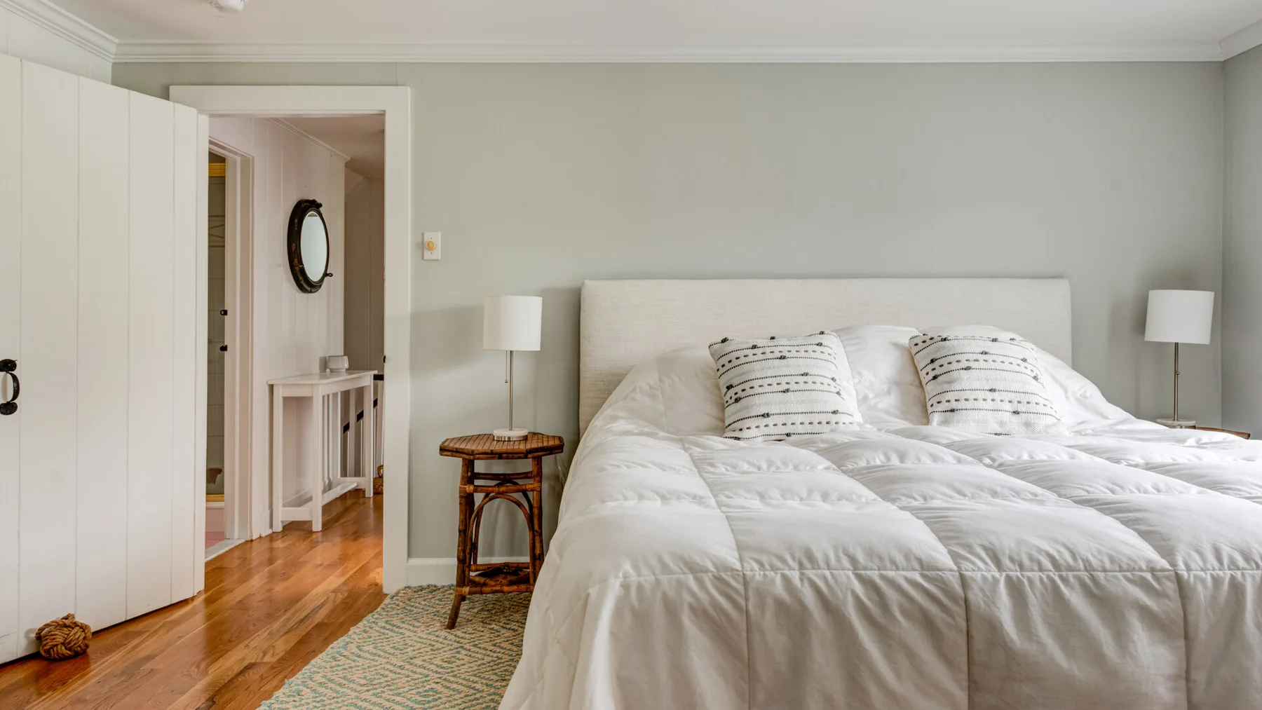 A bedroom with a large bed, white bedding, and a small bedside table.