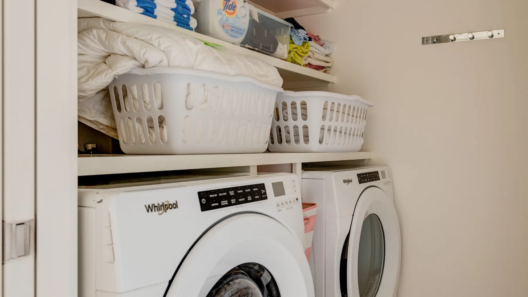 A laundry area with two washing machines and shelves of linens and supplies.