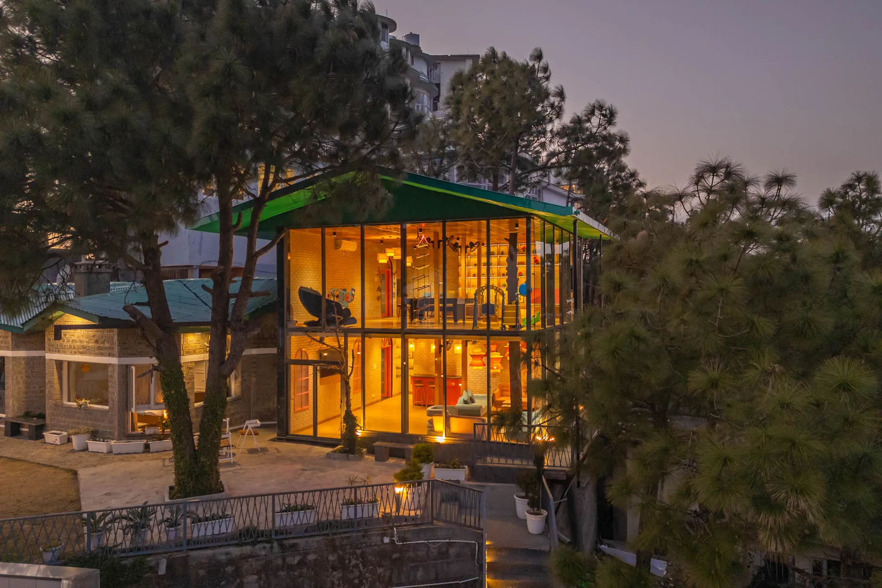 Un edificio moderno con fachada de vidrio brilla al atardecer entre árboles.