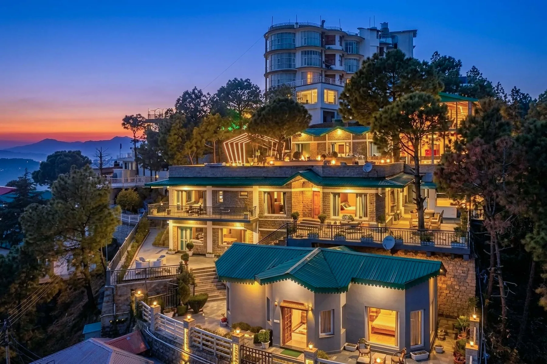 A hillside resort complex glows with lights beneath a colorful dusk sky.