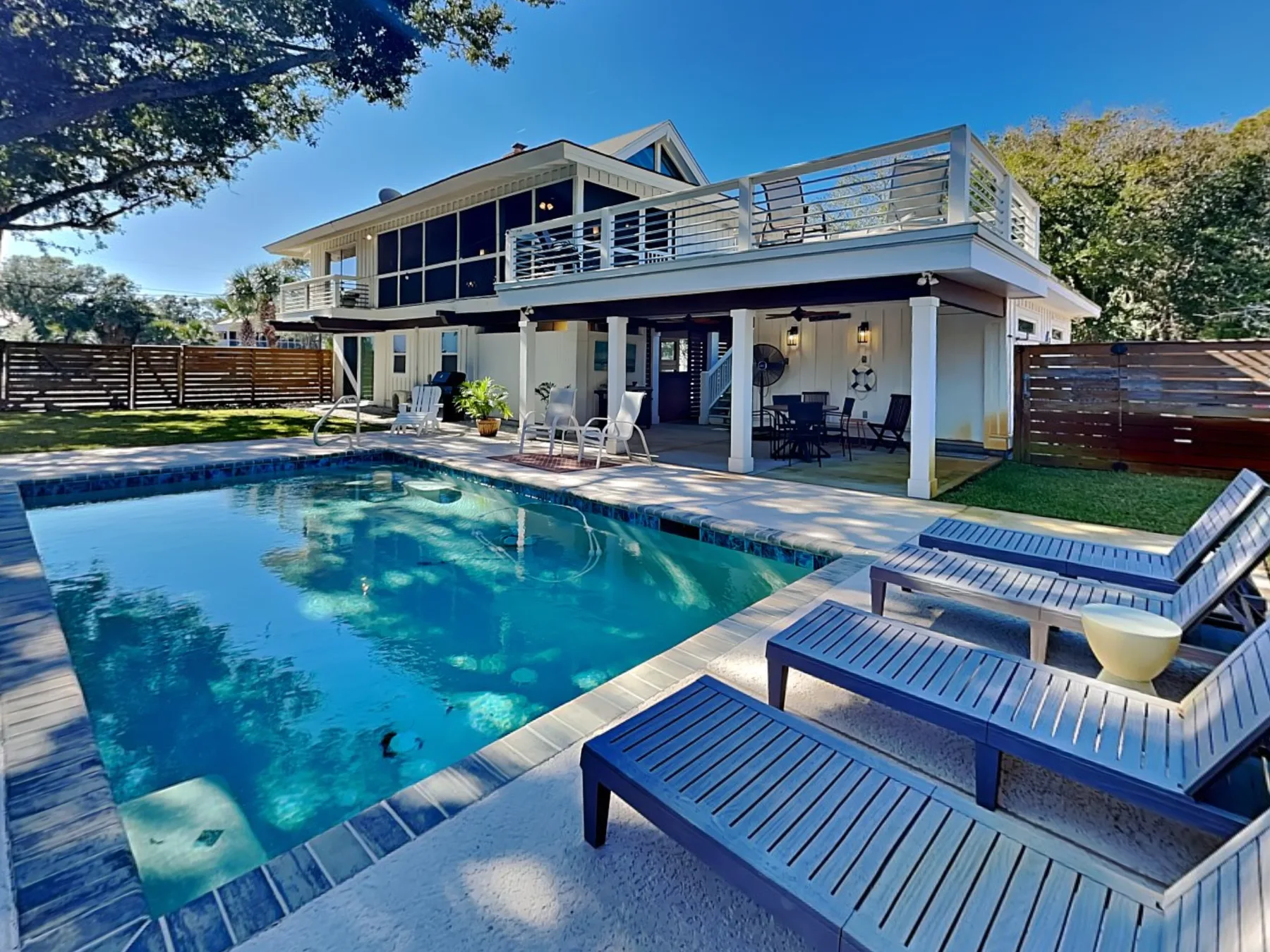 A swimming pool beside a modern house with outdoor seating.