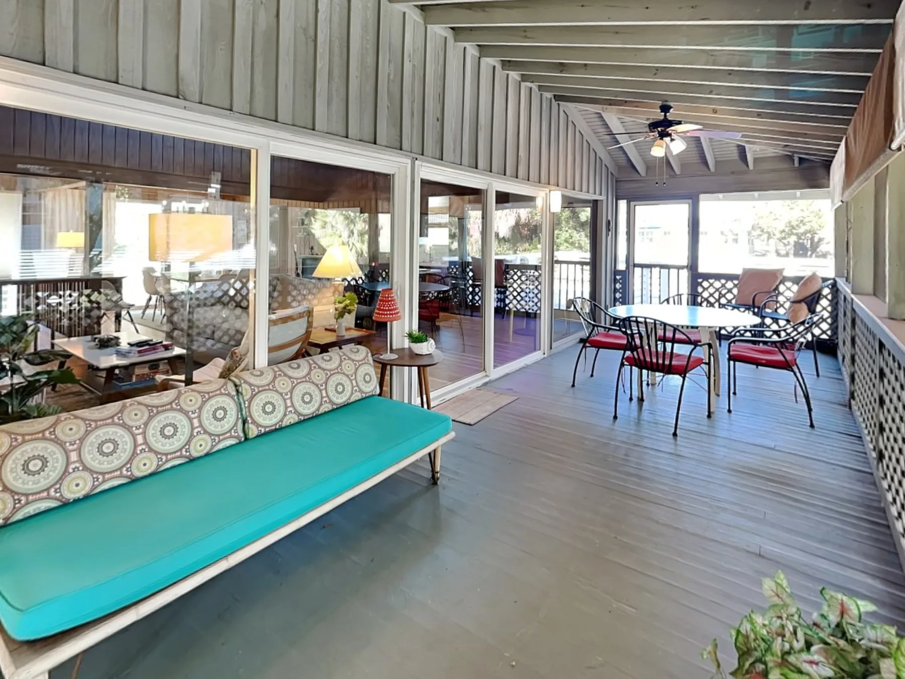 A covered patio with a cushioned bench, dining table, and chairs.
