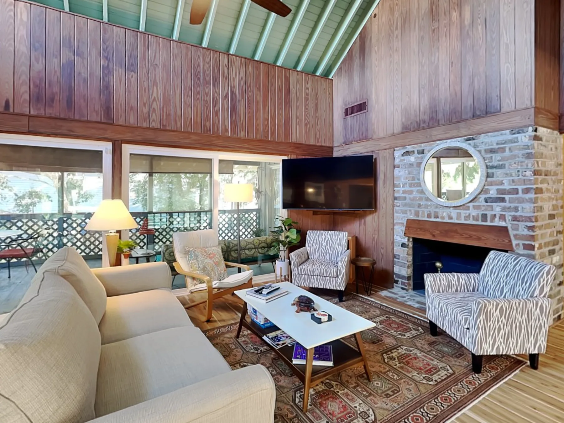 A wood-paneled living room with seating, a television, and a brick fireplace.