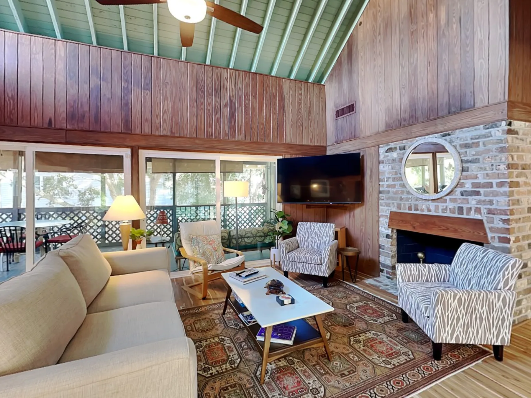A living room with seating, a television, and a brick fireplace.