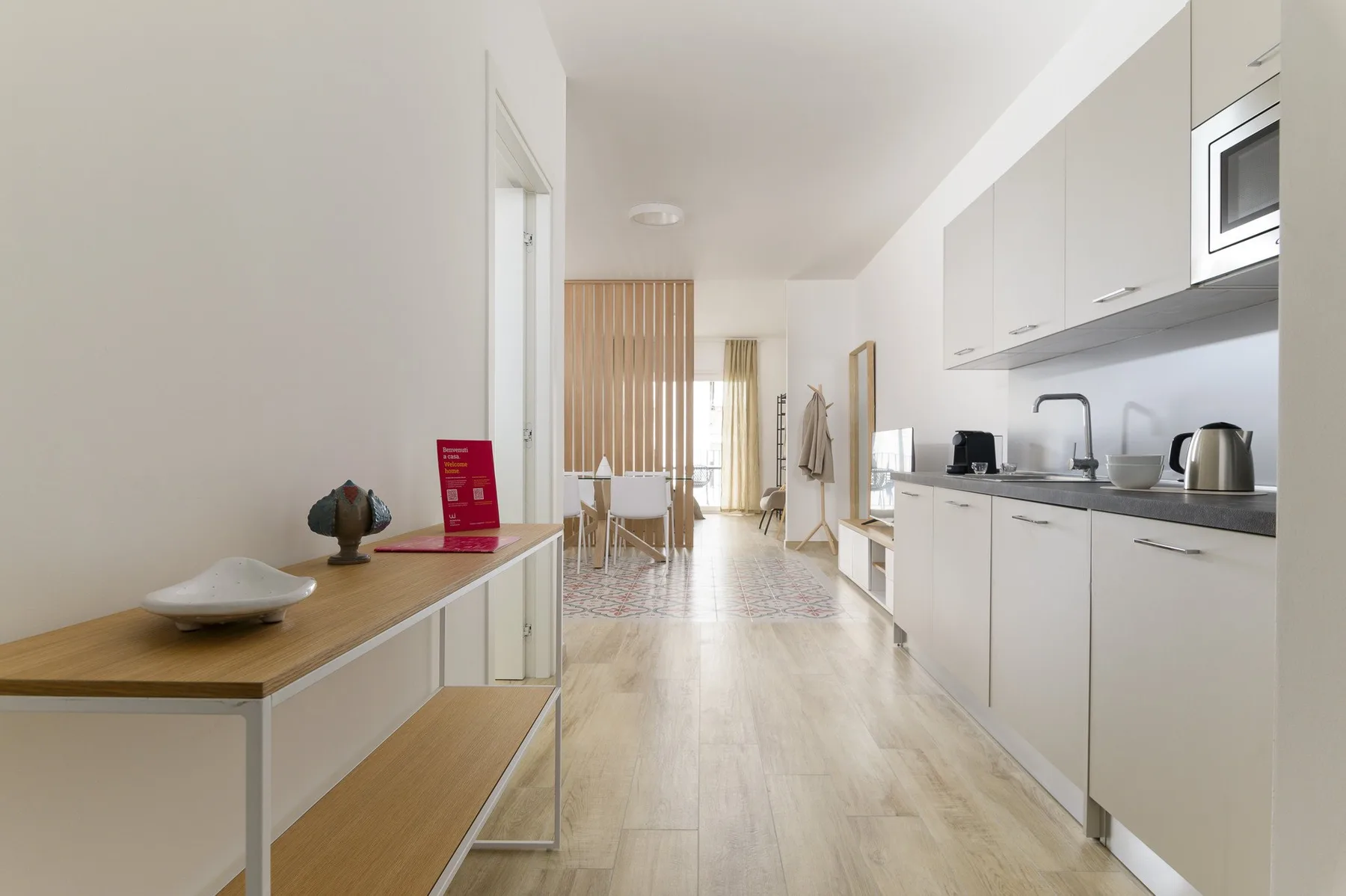 A bright open-plan kitchen and dining area with white cabinetry and a table.