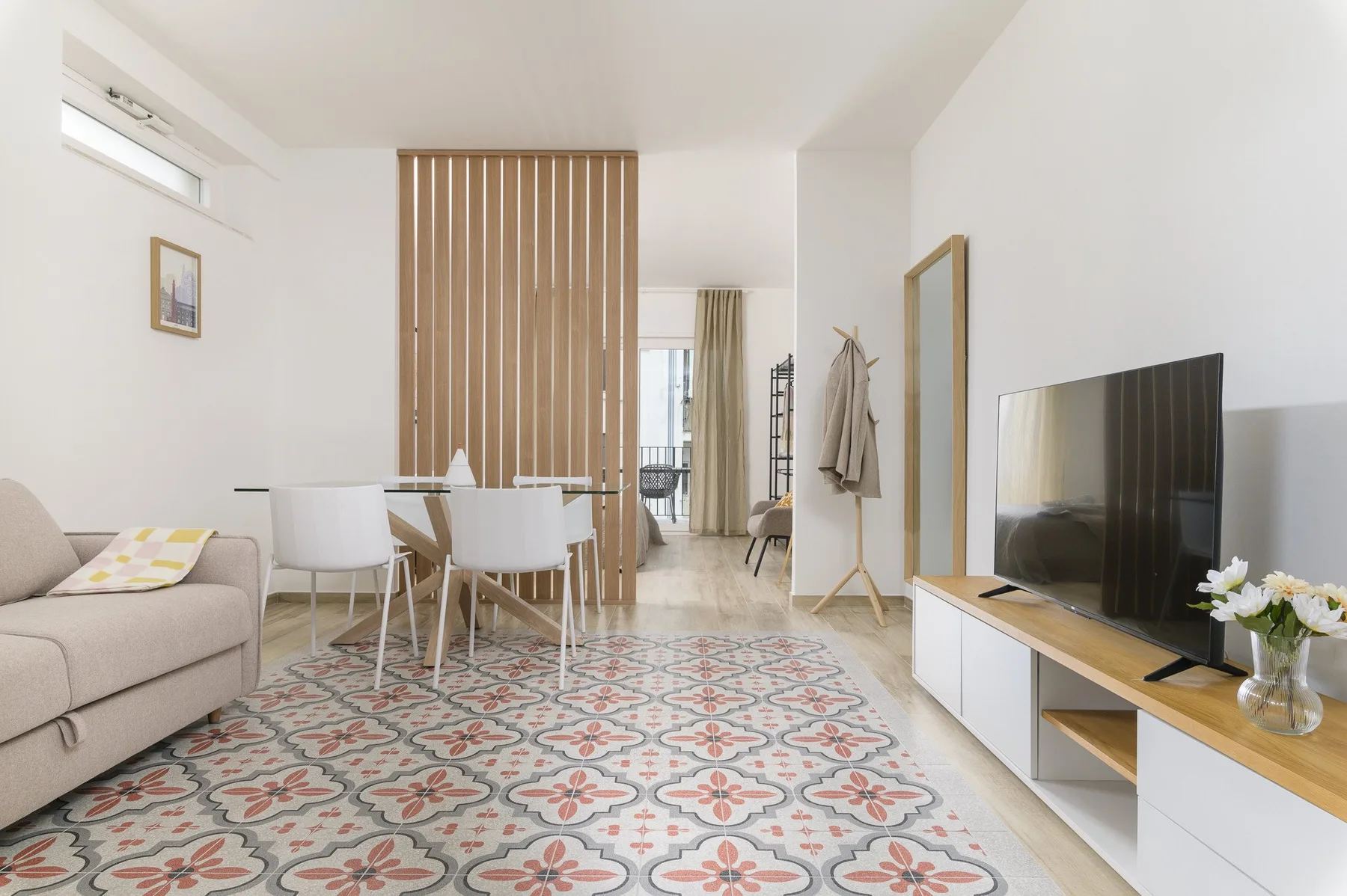 A bright living and dining area with patterned tile flooring and a television.