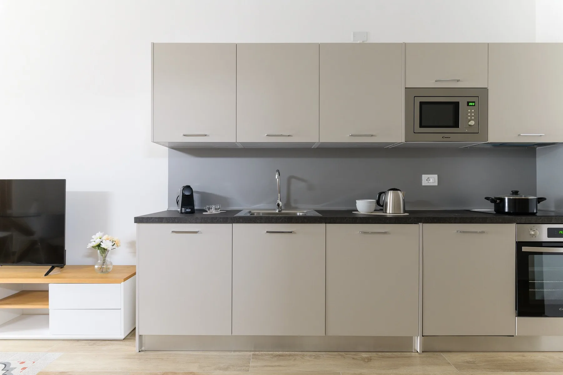 A modern kitchen with pale cabinets, a countertop, and built-in appliances.