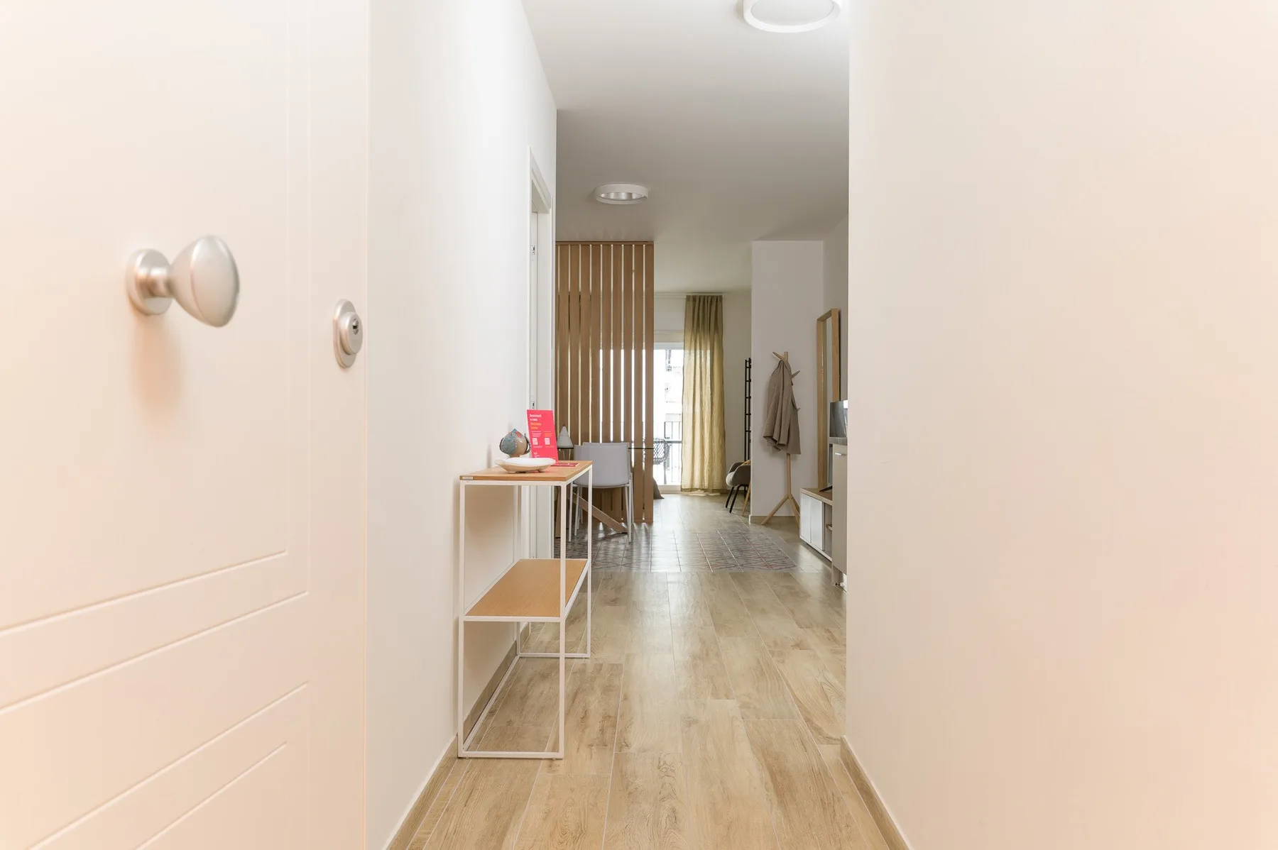 A bright hallway with a narrow console table and a wooden slatted divider.