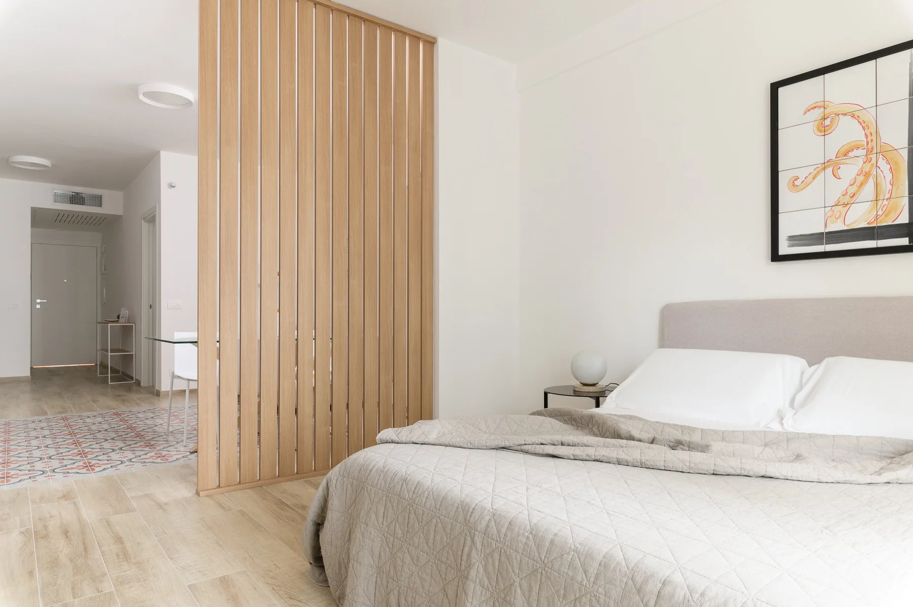 A bedroom with a bed beside a wooden slatted divider.