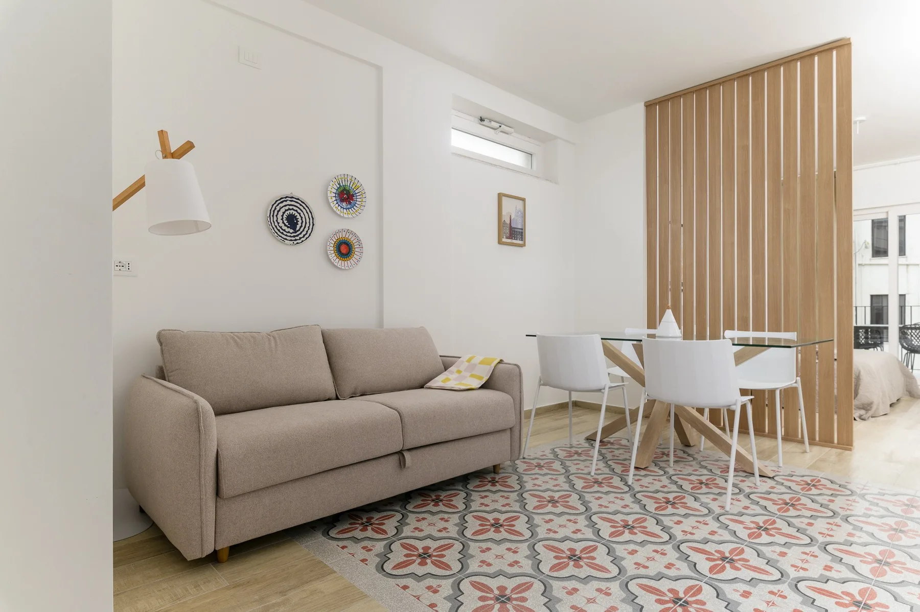 A bright living and dining area with a beige sofa and a dining table.