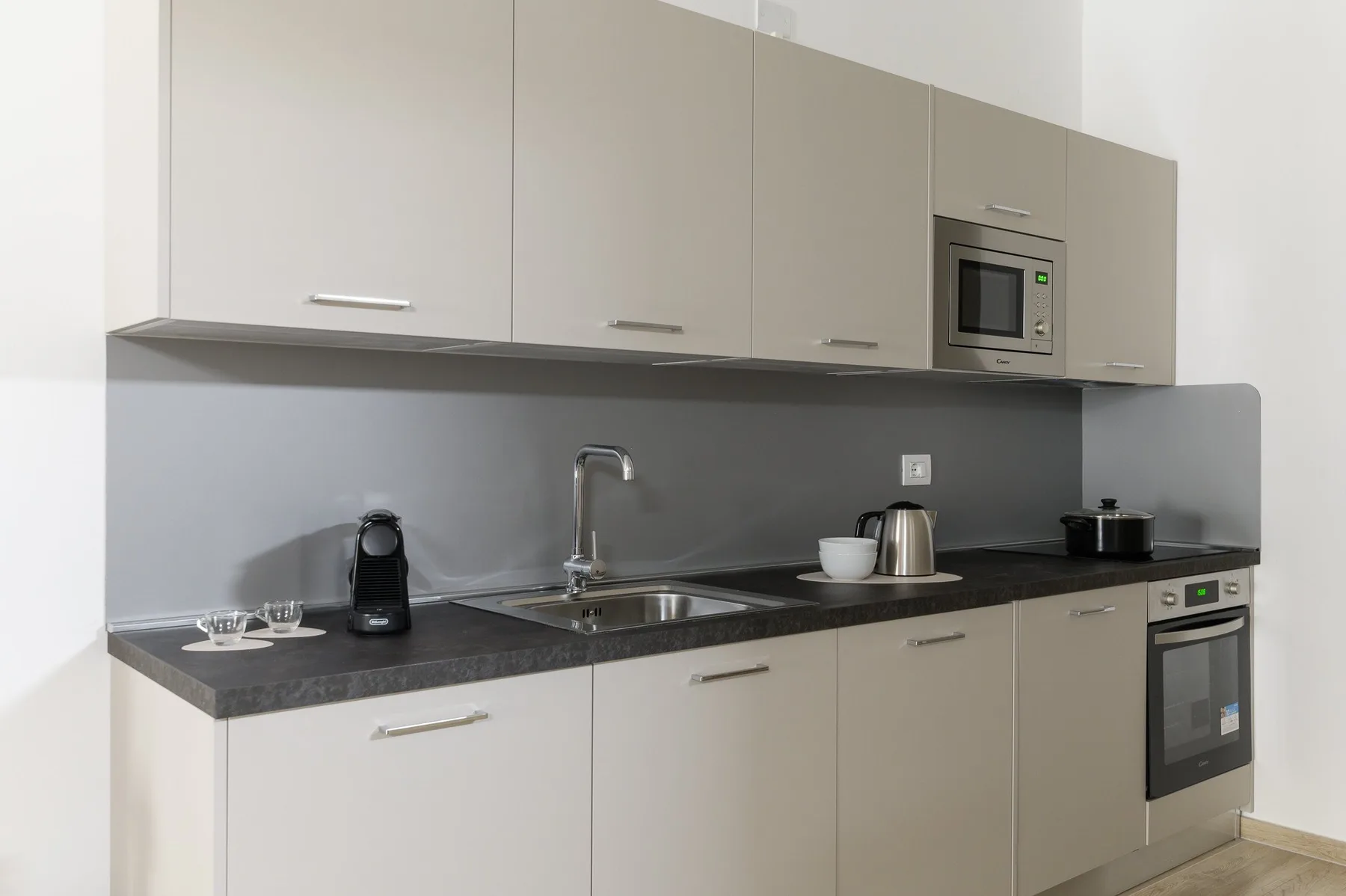 A modern kitchen with light cabinets, a dark countertop, and a sink.