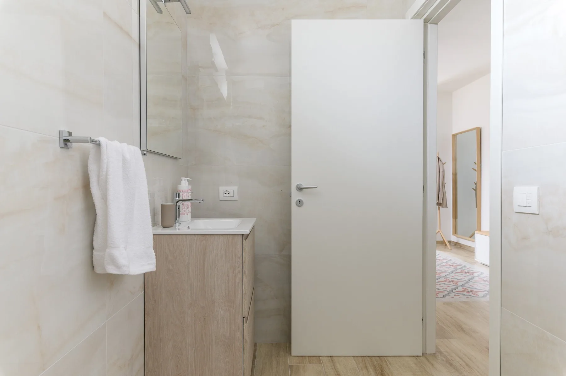 A bathroom vanity and towel are visible beside an open door.