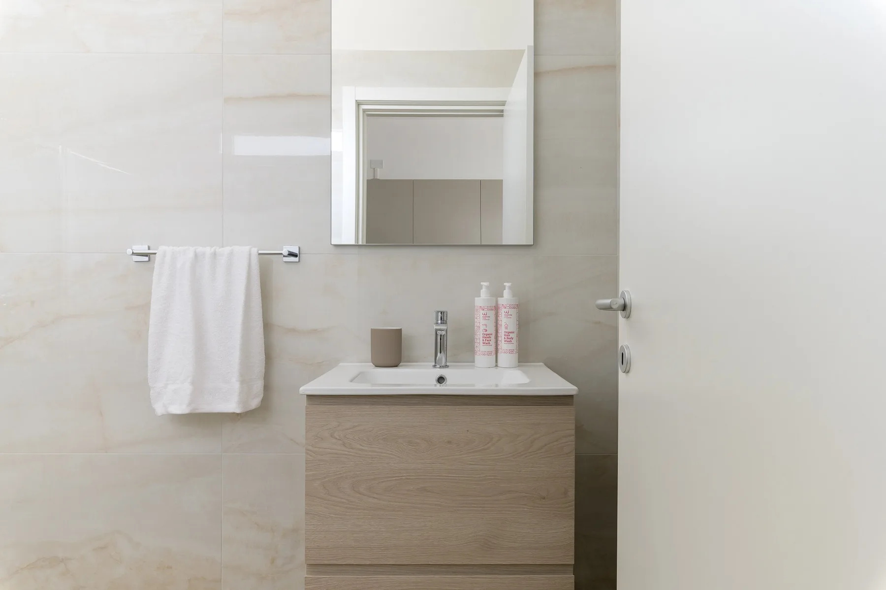 A bright bathroom vanity with a sink, mirror, and towel.
