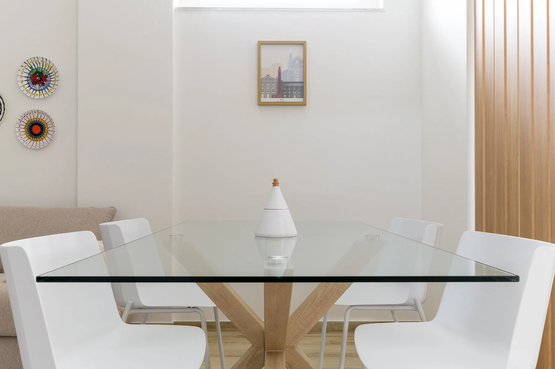 A bright dining area with a glass table and white seating.