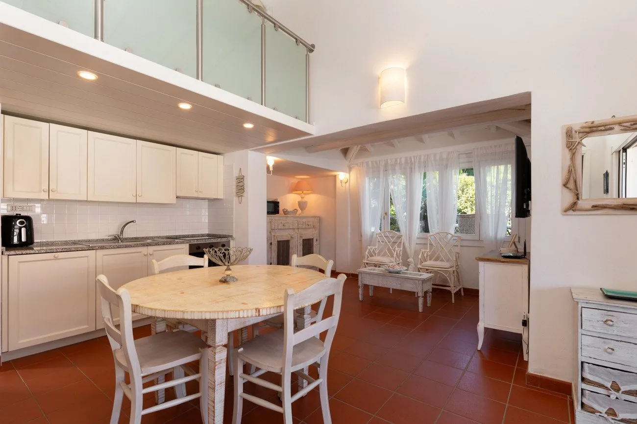 Una luminosa sala-comedor de planta abierta, con una mesa redonda y asientos junto a las ventanas.